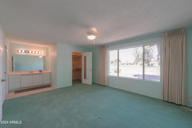 interior space with ceiling fan, a textured ceiling, a closet, a spacious closet, and light carpet