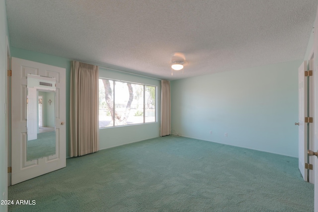 spare room featuring a textured ceiling and light carpet