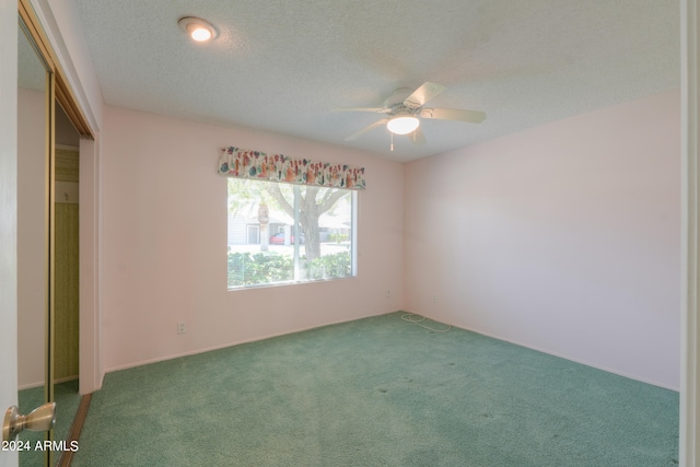 carpeted empty room featuring ceiling fan and a textured ceiling