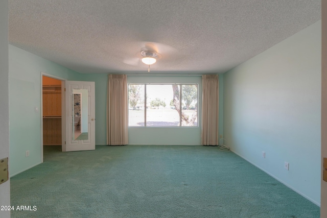 unfurnished bedroom with carpet, a walk in closet, and a textured ceiling