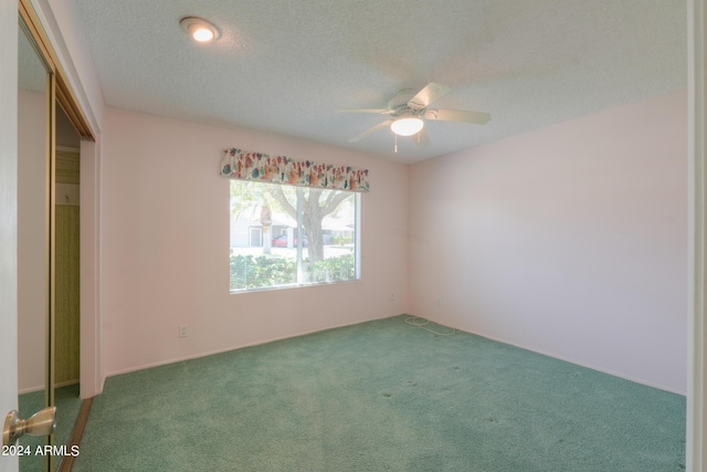 empty room featuring a textured ceiling, ceiling fan, and carpet flooring