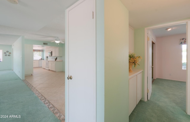 hall with light colored carpet, visible vents, and light tile patterned floors