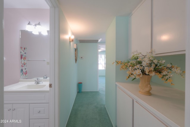 hallway with light colored carpet and a sink