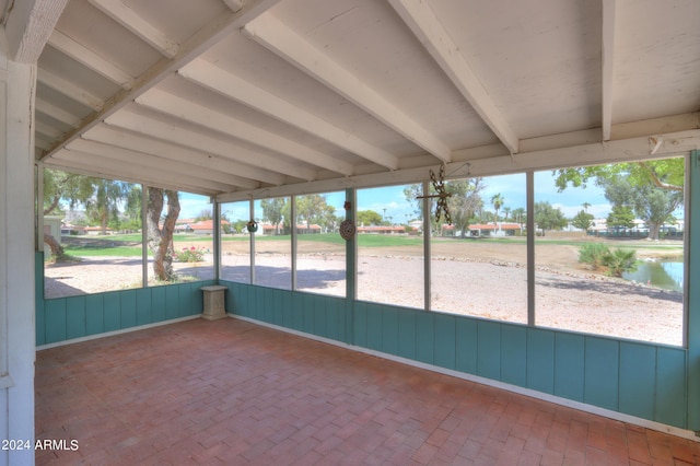 unfurnished sunroom featuring beam ceiling and plenty of natural light