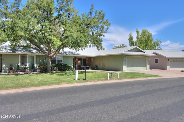 ranch-style home featuring a garage, concrete driveway, and a front lawn