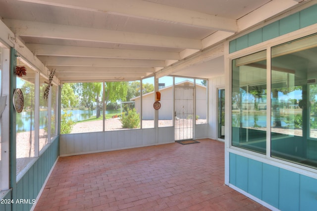 unfurnished sunroom featuring a water view, a healthy amount of sunlight, and beam ceiling