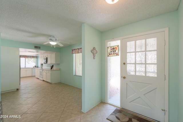 tiled entrance foyer with ceiling fan and a textured ceiling