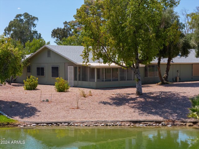 rear view of property with a sunroom and a water view