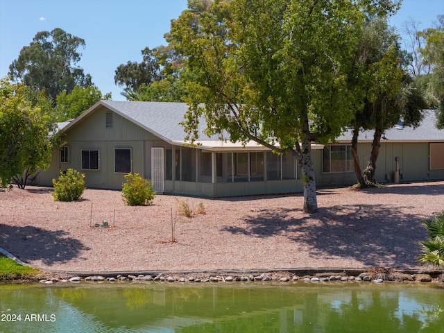 back of property with a sunroom and a water view