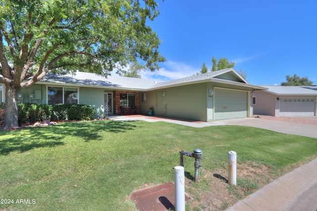 ranch-style house featuring concrete driveway, an attached garage, and a front yard