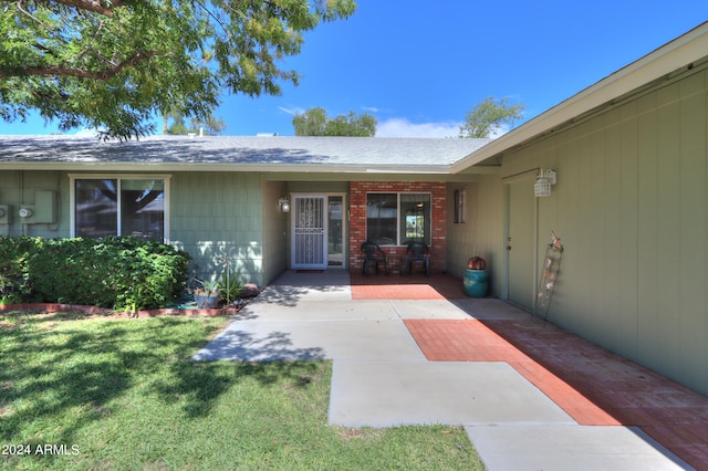 view of exterior entry with a patio and a yard