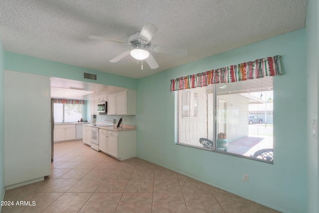 kitchen featuring light countertops, white electric range, stainless steel microwave, visible vents, and white cabinets