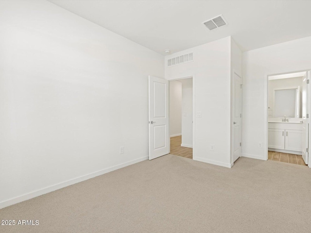 unfurnished bedroom with light carpet, sink, and ensuite bath