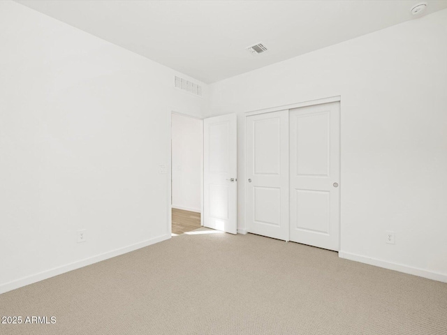 unfurnished bedroom featuring a closet and light carpet