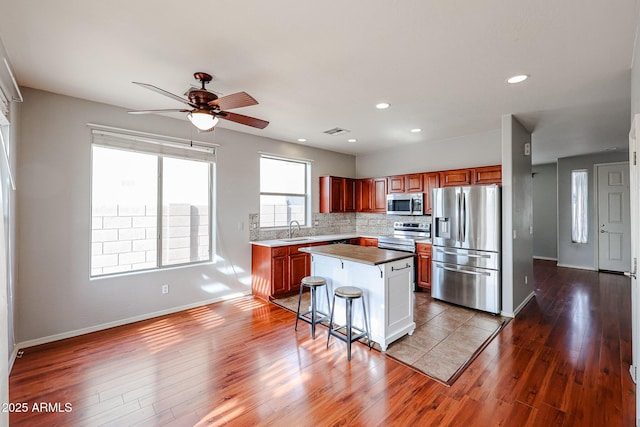 kitchen featuring backsplash, appliances with stainless steel finishes, wood finished floors, and a sink