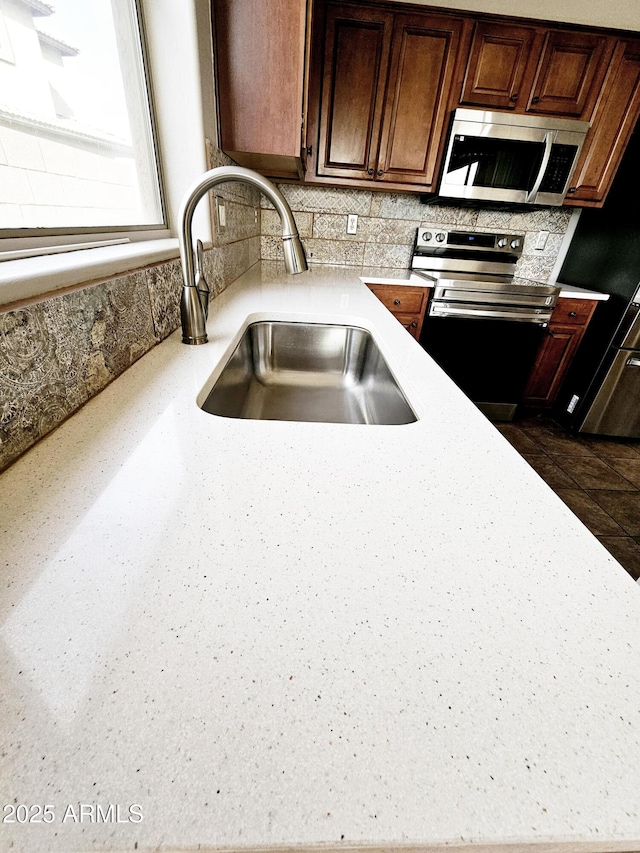 kitchen featuring a sink, decorative backsplash, appliances with stainless steel finishes, and light countertops