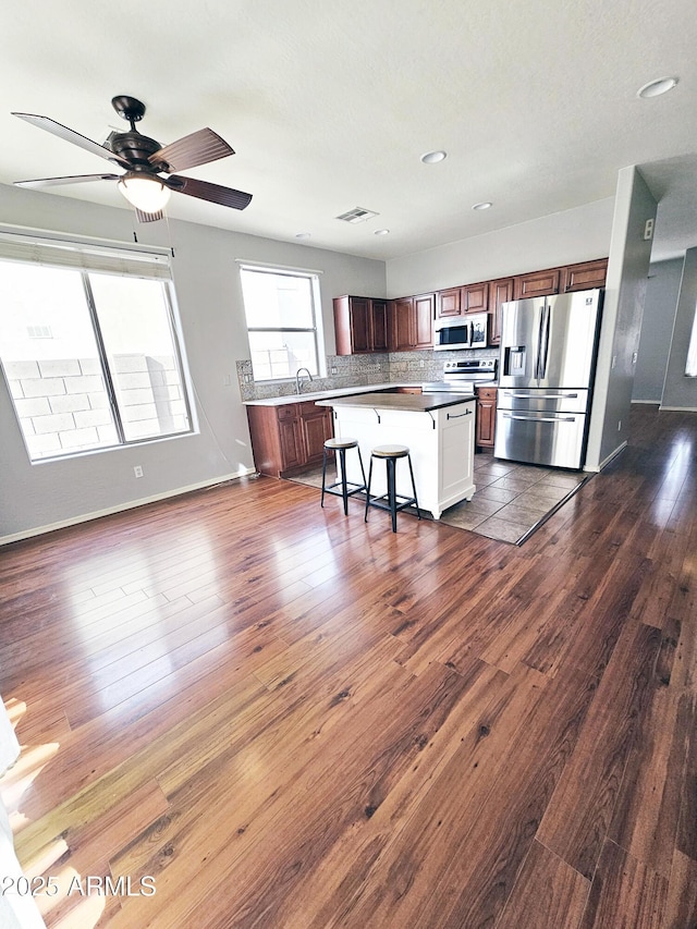 kitchen with visible vents, dark wood finished floors, a kitchen bar, appliances with stainless steel finishes, and a sink