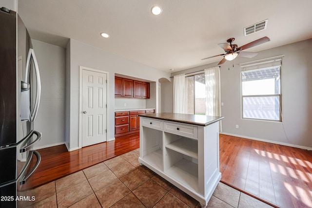 kitchen featuring visible vents, open shelves, light wood-style floors, and stainless steel fridge with ice dispenser