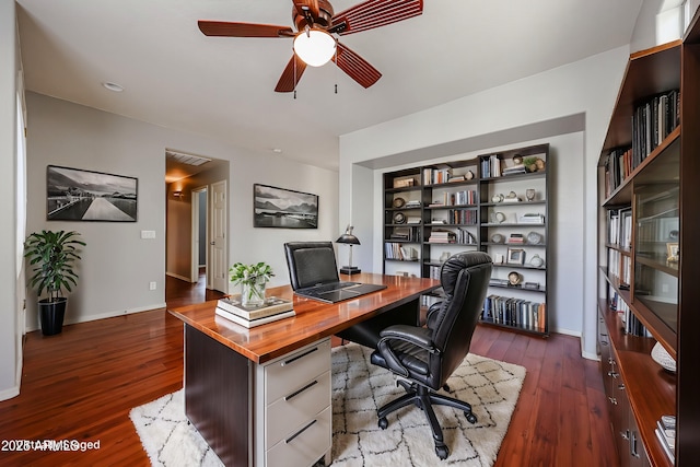 office area featuring baseboards, dark wood-type flooring, and a ceiling fan