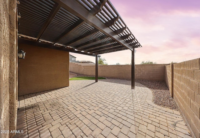 patio terrace at dusk featuring a fenced backyard and a pergola