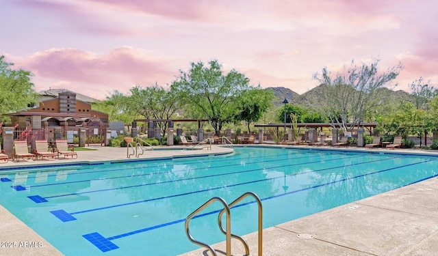 pool at dusk with a community pool, a patio, and fence