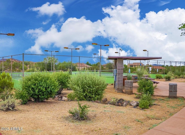 surrounding community featuring a tennis court and fence