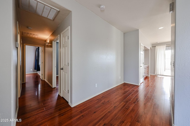 hall featuring dark wood finished floors, visible vents, and baseboards