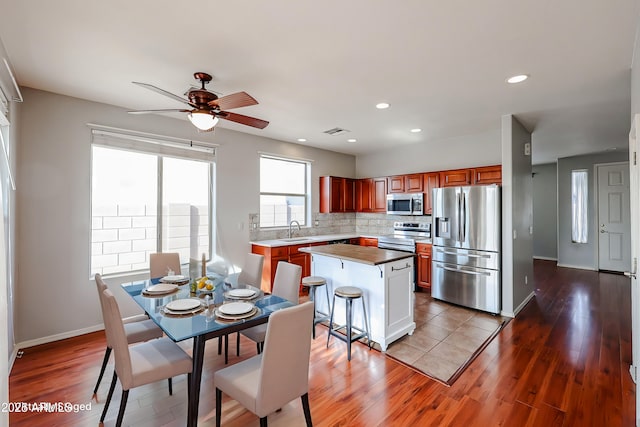 kitchen featuring a sink, tasteful backsplash, wood finished floors, appliances with stainless steel finishes, and baseboards