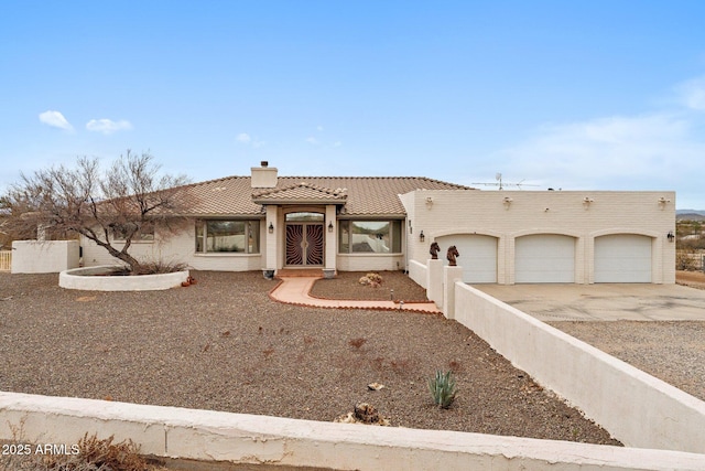 view of front of house featuring driveway, a tile roof, fence, a garage, and a chimney