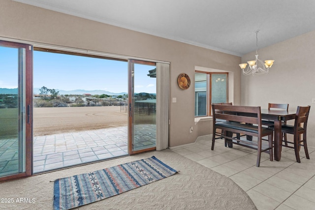 dining area with tile patterned flooring, a notable chandelier, a mountain view, and ornamental molding