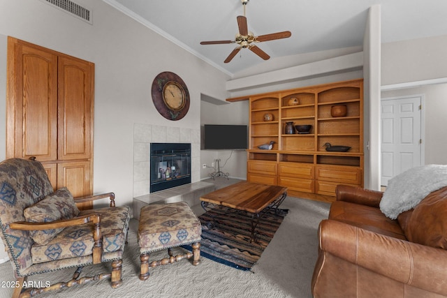 living area with visible vents, ornamental molding, a tiled fireplace, lofted ceiling, and ceiling fan