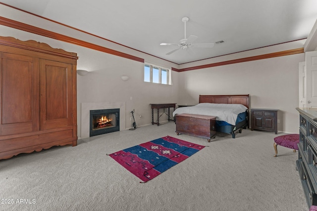 carpeted bedroom with a glass covered fireplace, ceiling fan, crown molding, and visible vents