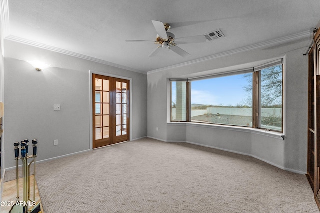 carpeted empty room with crown molding, french doors, visible vents, and baseboards