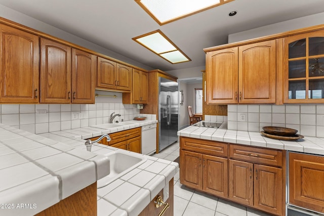 kitchen featuring a sink, tile countertops, built in refrigerator, and white dishwasher