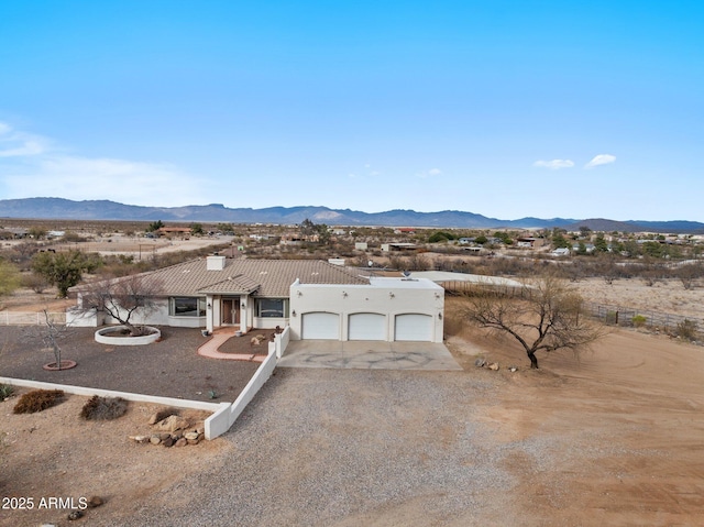 view of front facade with an attached garage, a tiled roof, stucco siding, driveway, and a mountain view