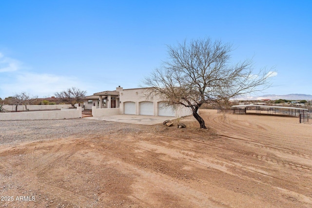 view of front of property with fence, driveway, an attached garage, a chimney, and stucco siding