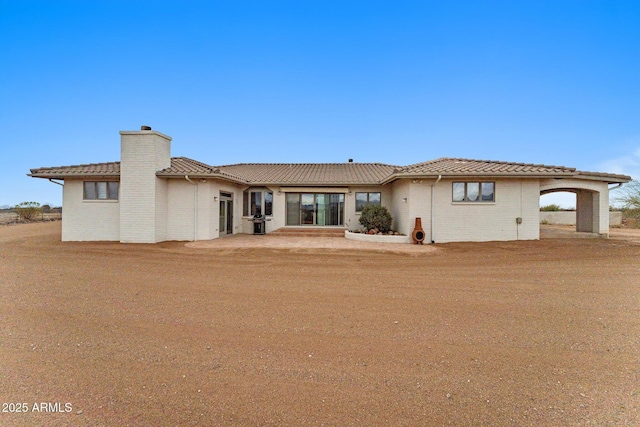 ranch-style home with a chimney and a tile roof