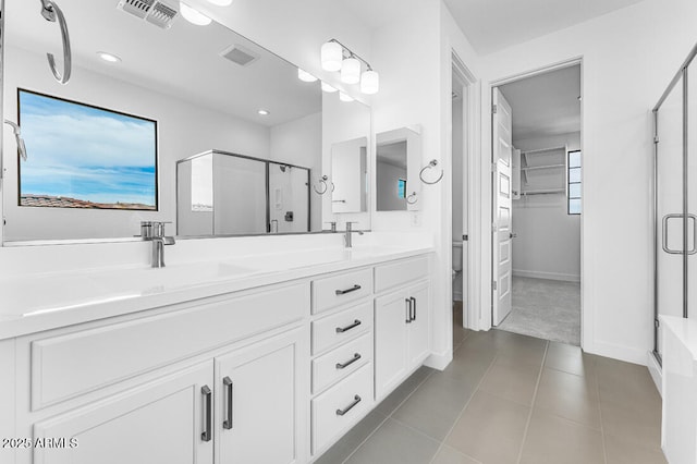 bathroom featuring visible vents, a shower stall, double vanity, tile patterned floors, and a sink