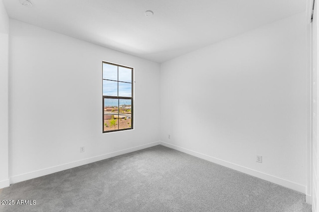 carpeted empty room featuring baseboards