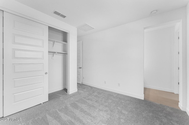 unfurnished bedroom featuring baseboards, carpet, a closet, and visible vents