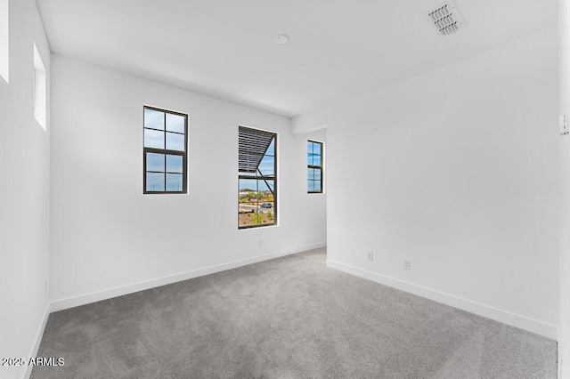 empty room with baseboards, carpet flooring, and visible vents