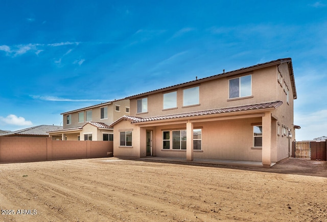 rear view of property with stucco siding, a fenced backyard, a tiled roof, and a patio area
