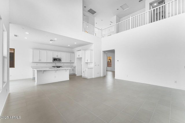 unfurnished living room featuring baseboards, visible vents, recessed lighting, and a sink