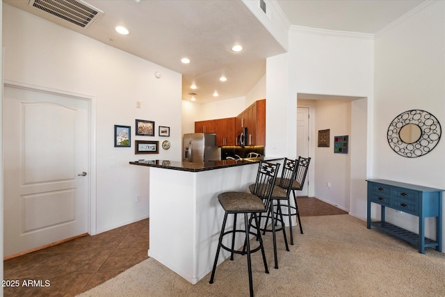 11640 N Tatum Blvd Unit 3091, Phoenix, AZ 85028 - kitchen with crown molding, visible vents, a breakfast bar, stainless steel appliances, and brown cabinets