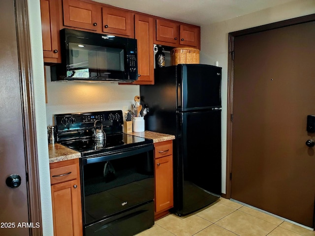 kitchen with brown cabinets, light countertops, light tile patterned flooring, and black appliances