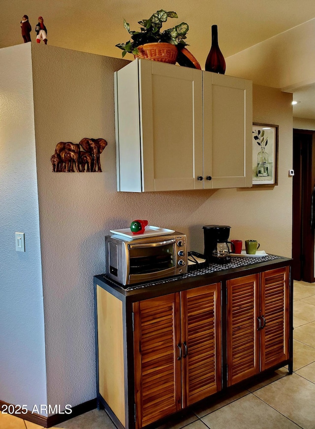 kitchen featuring light tile patterned floors, dark countertops, white cabinets, and a toaster