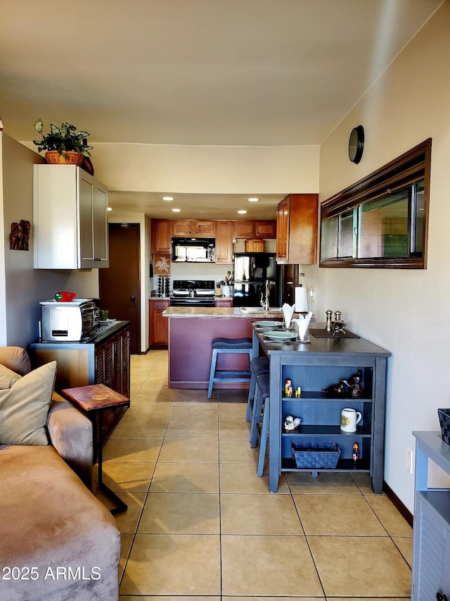 kitchen with light tile patterned floors, a peninsula, a sink, baseboards, and black appliances