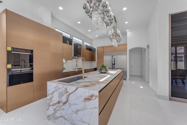 kitchen featuring sink, backsplash, double oven, built in fridge, and pendant lighting