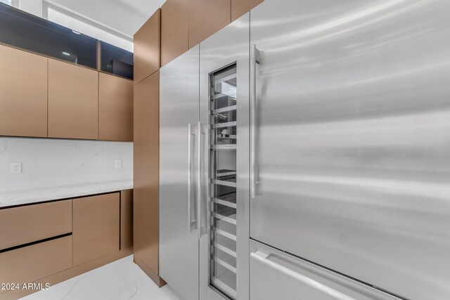 kitchen with backsplash, light stone countertops, and high end fridge