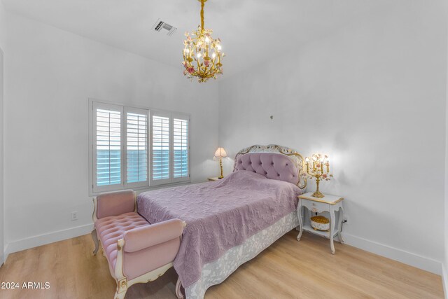 bedroom with light wood-type flooring and an inviting chandelier